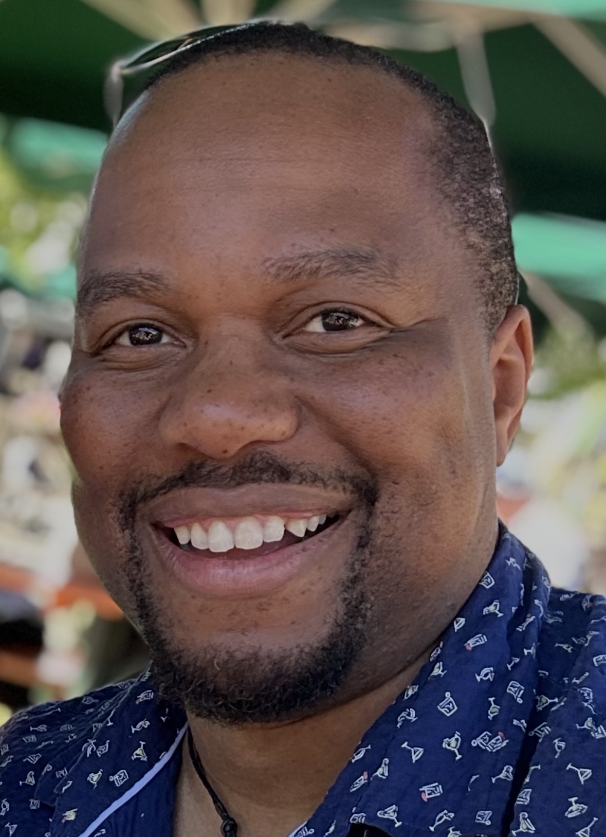 Shungu Patsika, smiling outdoors in a blue patterned shirt